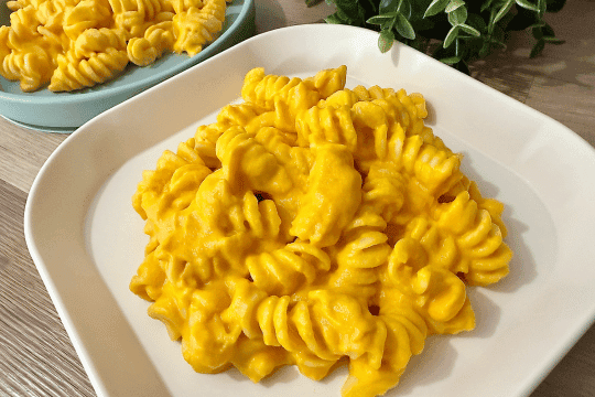 "Warm creamy carrot pasta served in a bowl, optionally topped with grated cheese for extra flavor."