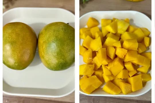Two whole, ripe green and yellow mangoes on a white plate next to a bowl of freshly diced golden mango chunks.