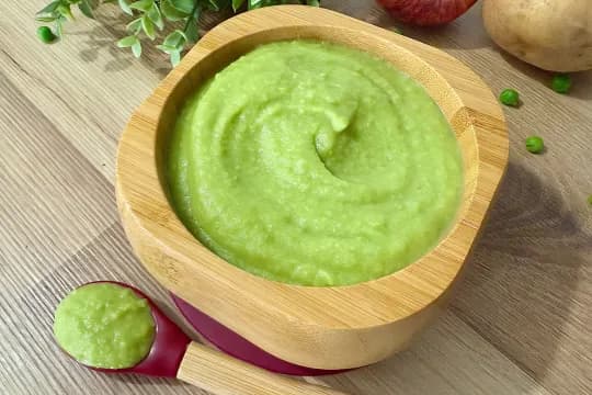 "Nutritious, smooth green pea and potato baby food, freshly prepared, served in an eco-friendly bamboo bowl with a spoon, highlighting healthy eating for infants."