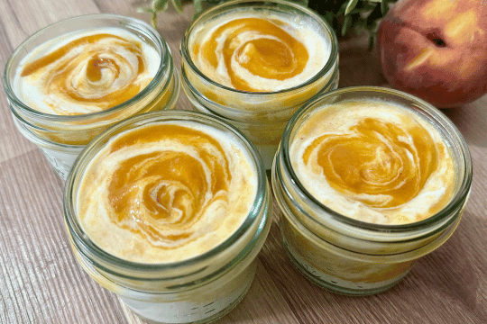 Peach yogurt being spooned into small airtight containers or jars, ready to be sealed and stored in the fridge.