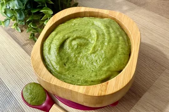 "Homemade spinach and butternut squash baby puree served in an eco-friendly bamboo bowl with a matching spoon on a wooden table."