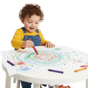 A toddler drawing colorful scribbles and dots with crayons on paper against a white background.