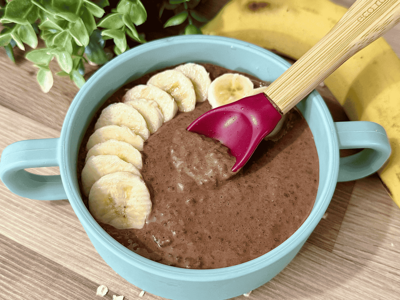 "Creamy chocolate chia pudding topped with fresh banana slices in a blue bowl with bamboo spoon – healthy vegan breakfast or snack option