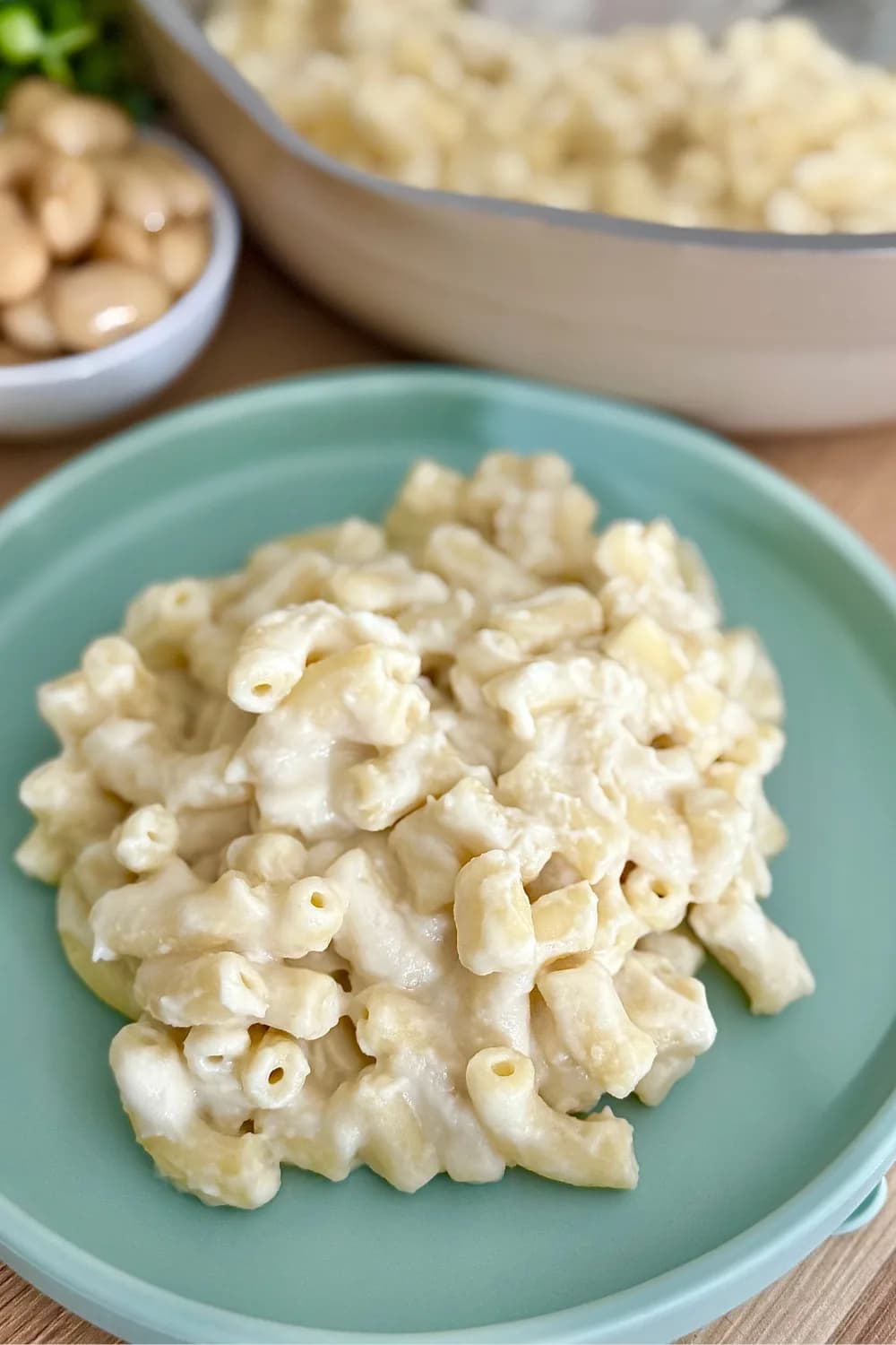 "Close-up of creamy vegan mac and cheese made with cauliflower and white beans, served on a blue plate"
