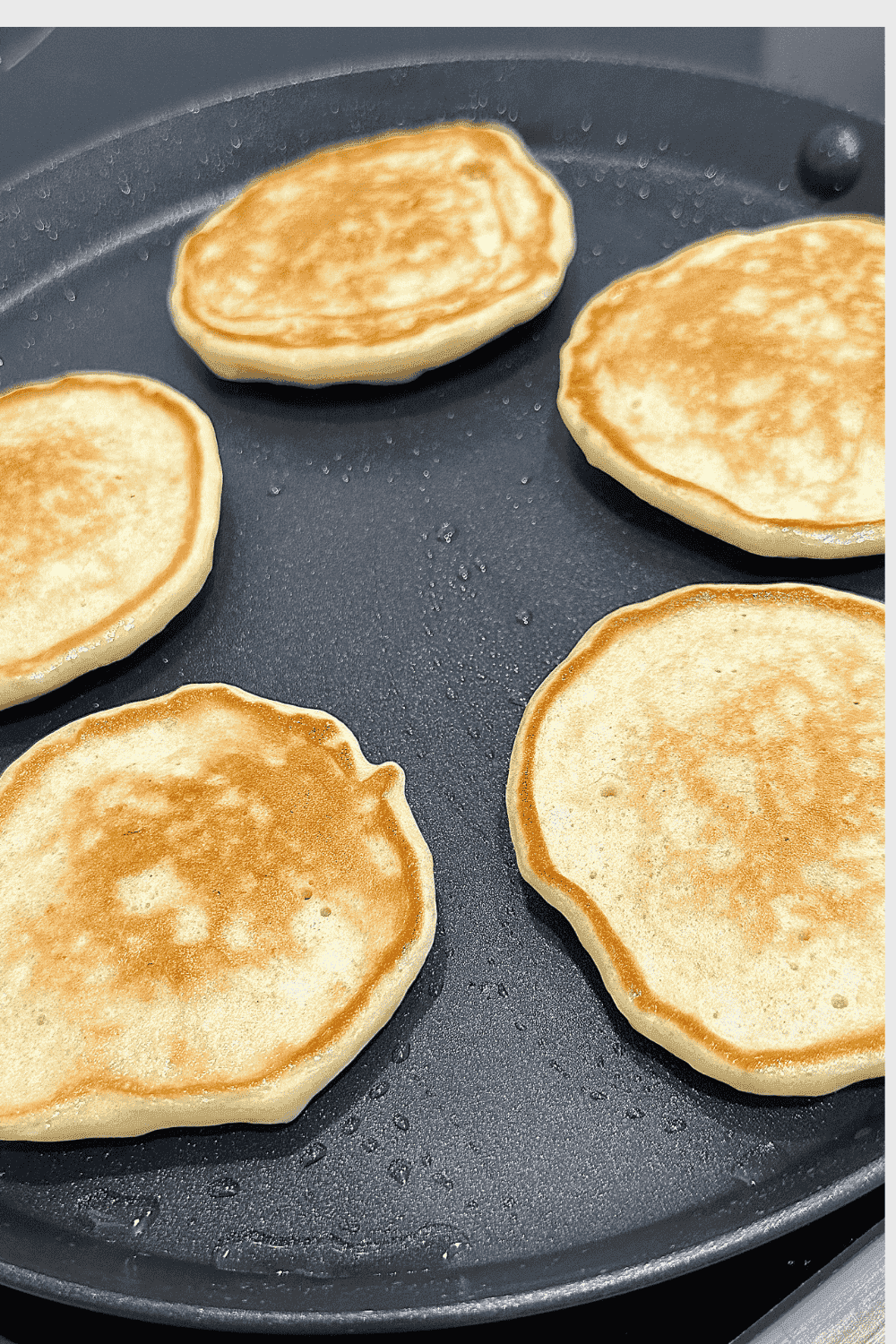 A stack of fluffy golden-brown banana pancakes made with Greek yoghurt, topped with banana slices , served on a plate for a wholesome breakfast or snack.