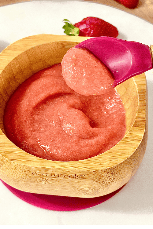 Alt Text: Smooth apple and strawberry puree served in a small white bowl, with fresh apple slices and strawberries on the side.