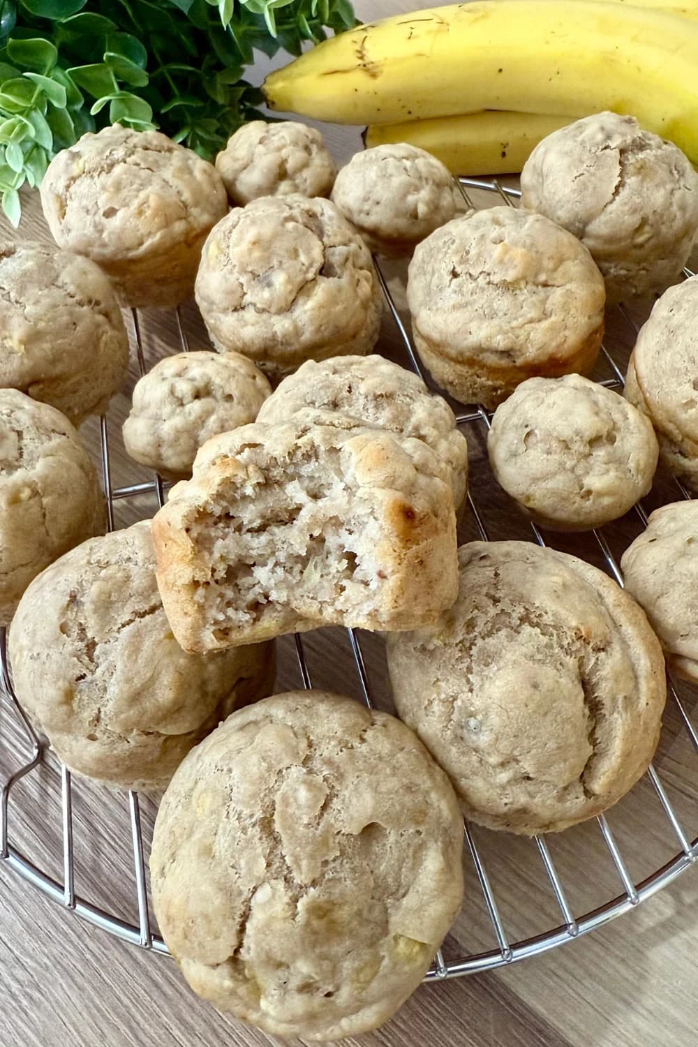 "Moist eggless banana muffins cooling on a wire rack with fresh bananas and green leaves in the background, perfect for a healthy snack or breakfast."